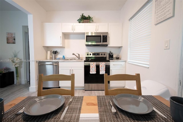 kitchen with a sink, stainless steel appliances, white cabinets, and light countertops