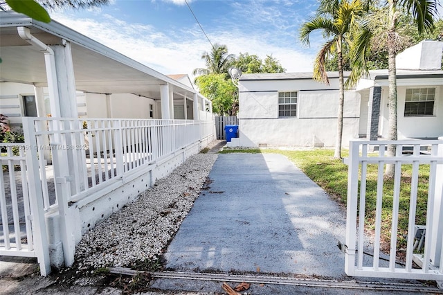 view of side of property featuring crawl space, covered porch, stucco siding, and fence