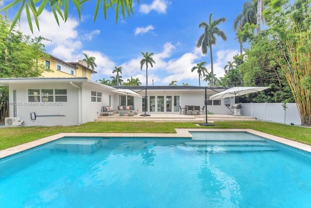 rear view of house featuring a fenced in pool, fence, stucco siding, a yard, and a patio area