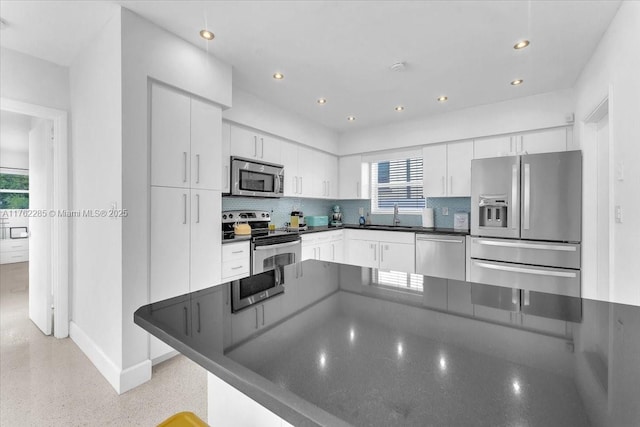 952 Hollywood Blvd, Hollywood, FL 33019 - kitchen with dark countertops, backsplash, appliances with stainless steel finishes, white cabinetry, and a sink