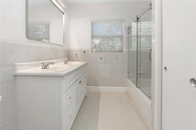 952 Hollywood Blvd, Hollywood, FL 33019 - bathroom featuring a sink, combined bath / shower with glass door, tile walls, wainscoting, and double vanity
