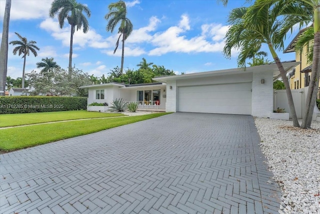 952 Hollywood Blvd, Hollywood, FL 33019 - view of front of home featuring decorative driveway, a front yard, an attached garage, and fence