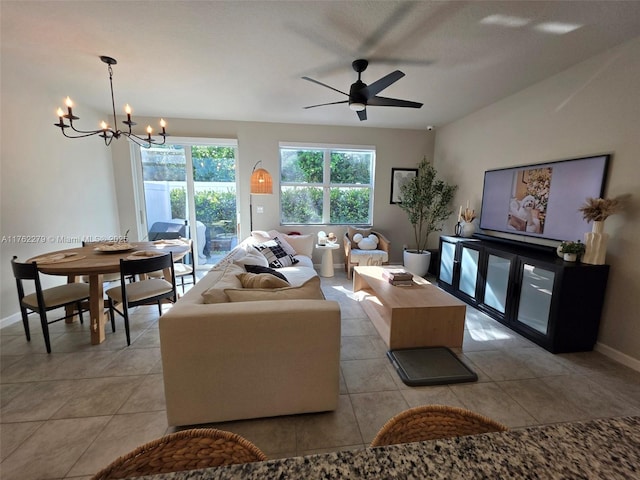 living room featuring light tile patterned floors, ceiling fan with notable chandelier, and baseboards