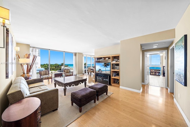 living room featuring baseboards, floor to ceiling windows, and light wood finished floors