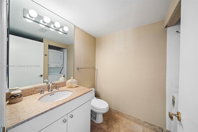 half bath with vanity, stacked washer / dryer, toilet, and visible vents