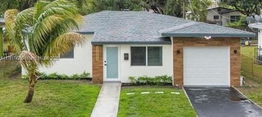 view of front of home featuring stucco siding, aphalt driveway, roof with shingles, a front yard, and an attached garage