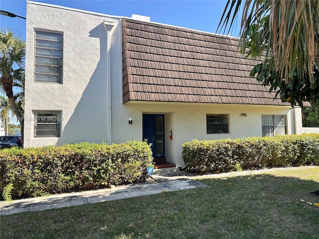 view of front of home featuring stucco siding and a front yard