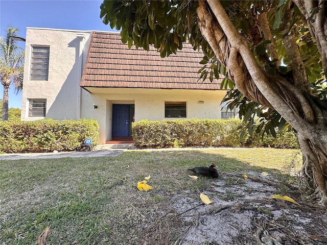 view of front of home with stucco siding, a front yard, and a tile roof