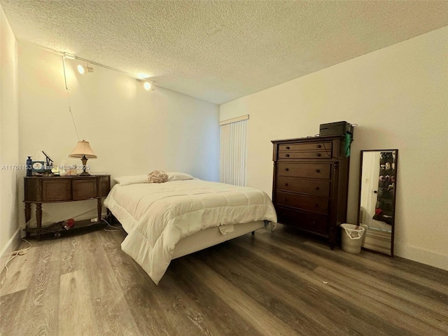 bedroom with a textured ceiling, baseboards, and wood finished floors