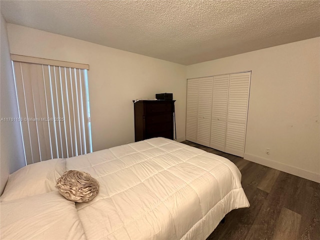 bedroom with a closet, baseboards, a textured ceiling, and wood finished floors