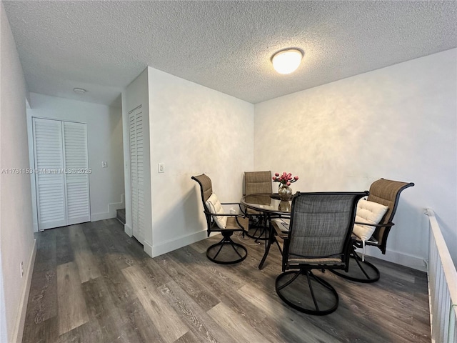 dining room featuring a textured ceiling, baseboards, and wood finished floors