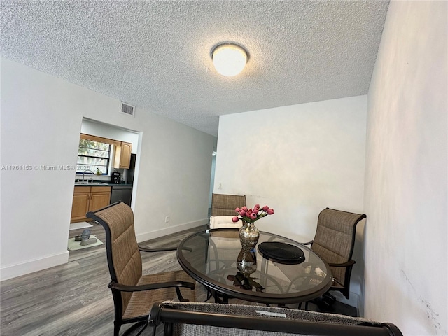 dining space featuring visible vents, baseboards, a textured ceiling, and dark wood-style floors