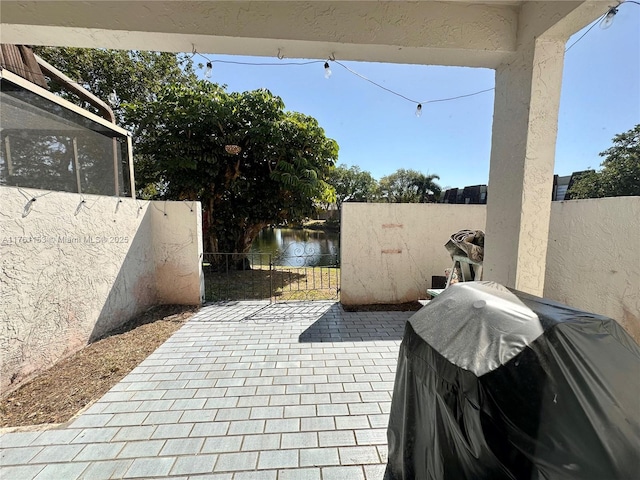 view of patio featuring a gate, a grill, fence private yard, and a water view