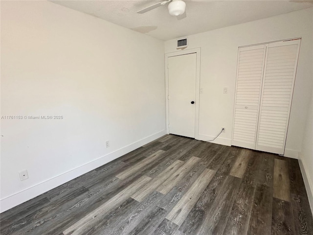 unfurnished bedroom featuring visible vents, dark wood-type flooring, a closet, baseboards, and ceiling fan