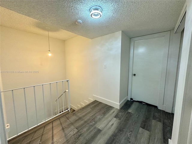 interior space featuring wood finished floors, baseboards, and a textured ceiling