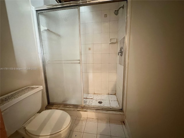 full bath featuring tile patterned flooring, a shower stall, and toilet