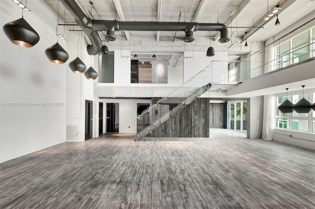 unfurnished living room featuring wood finished floors and a towering ceiling