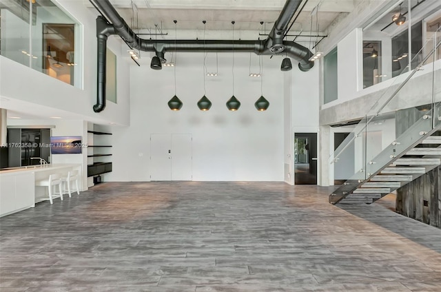 unfurnished living room with wood finished floors, a high ceiling, and stairs