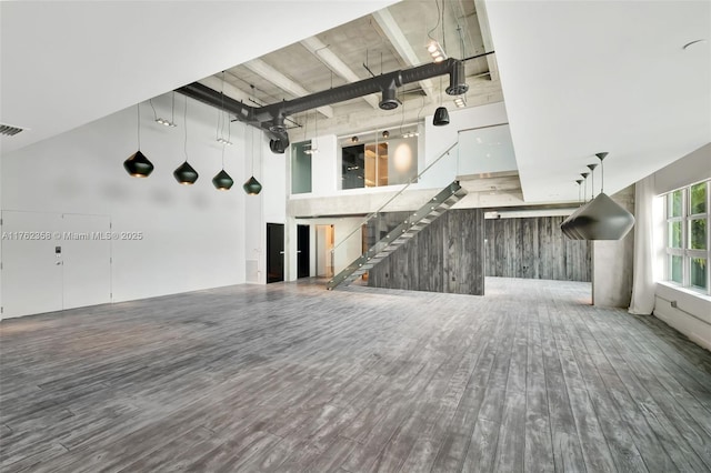unfurnished living room with a towering ceiling, wood finished floors, and visible vents