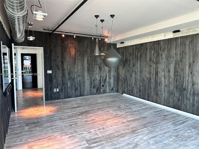 spare room featuring track lighting, wooden walls, and wood finished floors