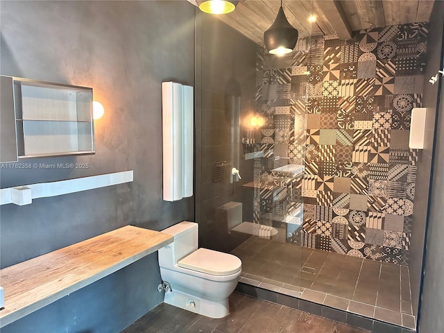 full bathroom featuring toilet, wood finished floors, and a tile shower