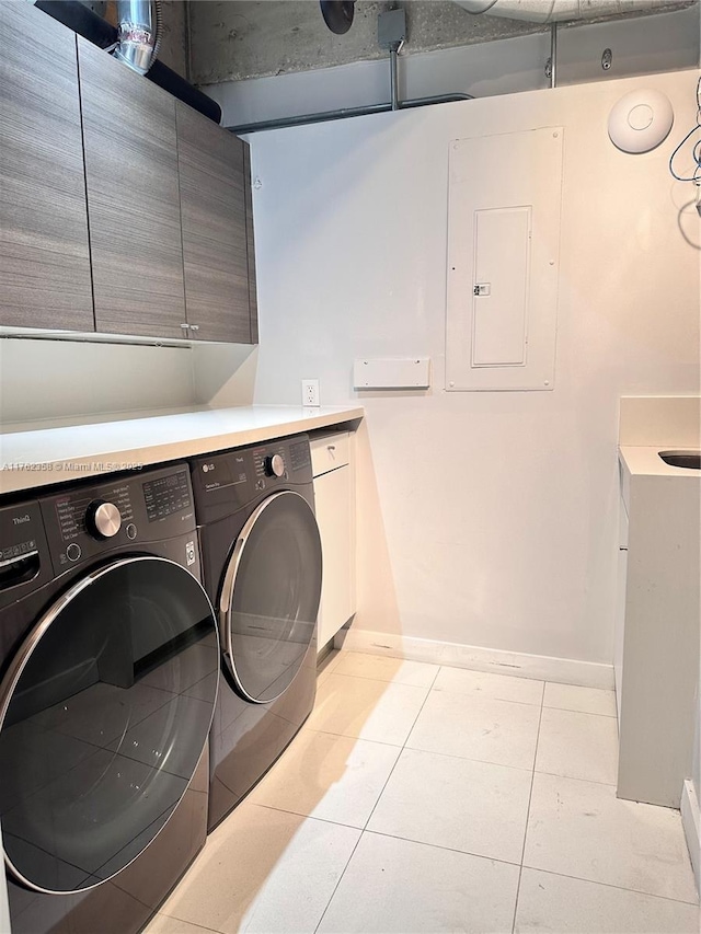 washroom with light tile patterned floors, baseboards, washing machine and clothes dryer, electric panel, and cabinet space