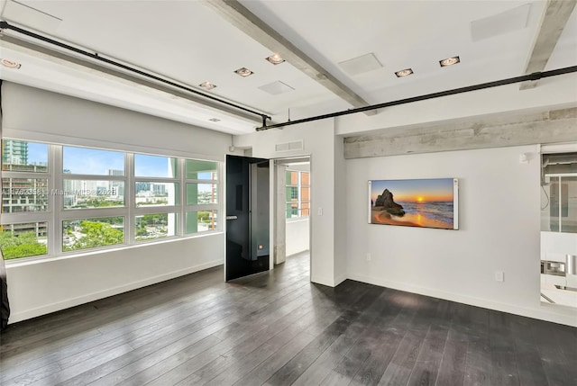 empty room with baseboards, visible vents, and dark wood-style floors