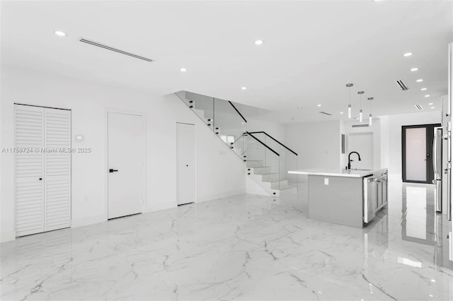 kitchen featuring a center island with sink, recessed lighting, open floor plan, and light countertops