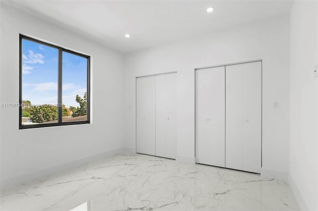 unfurnished bedroom featuring recessed lighting, baseboards, two closets, and marble finish floor