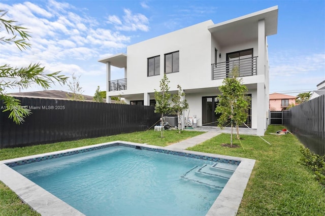 back of property with a fenced in pool, stucco siding, a lawn, a balcony, and a fenced backyard