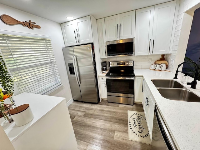 kitchen featuring a sink, white cabinetry, stainless steel appliances, light countertops, and decorative backsplash