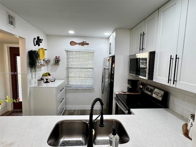 kitchen with visible vents, a sink, stainless steel appliances, light countertops, and backsplash