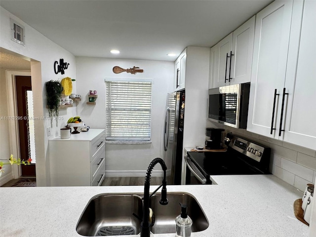 kitchen with decorative backsplash, stainless steel appliances, light countertops, a sink, and visible vents