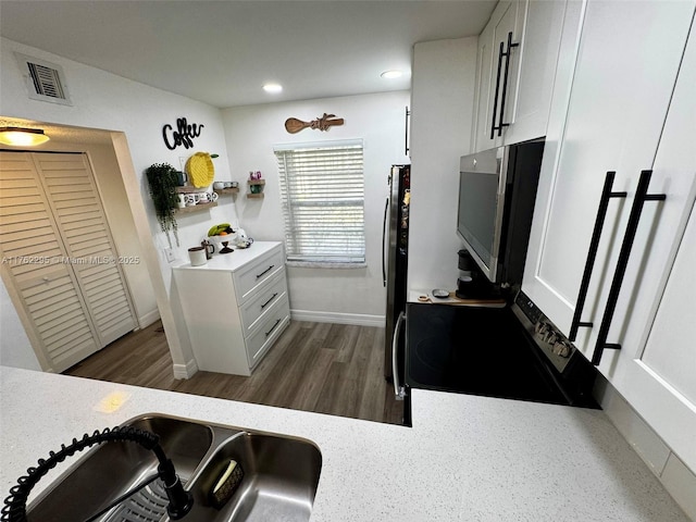 kitchen with visible vents, a sink, white cabinetry, freestanding refrigerator, and light countertops