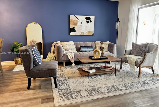 living room featuring an accent wall, wood finished floors, and baseboards