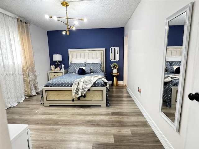 bedroom featuring baseboards, a textured ceiling, and wood finished floors