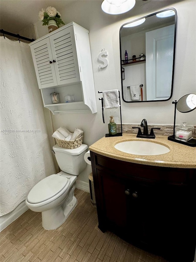 full bath with toilet, a shower with curtain, wood finished floors, and vanity
