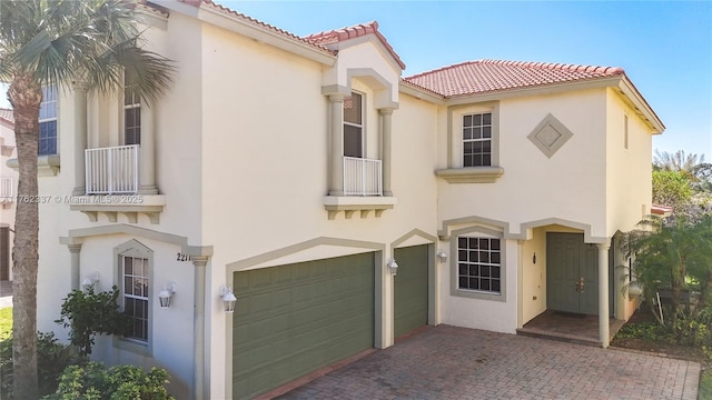 mediterranean / spanish-style home featuring stucco siding, decorative driveway, a garage, and a tiled roof