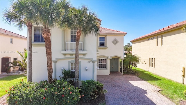 mediterranean / spanish house featuring stucco siding, a balcony, driveway, and a tile roof