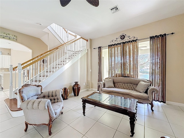 tiled living area featuring stairs, baseboards, visible vents, and ceiling fan