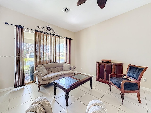 living area with light tile patterned floors, visible vents, baseboards, and a ceiling fan