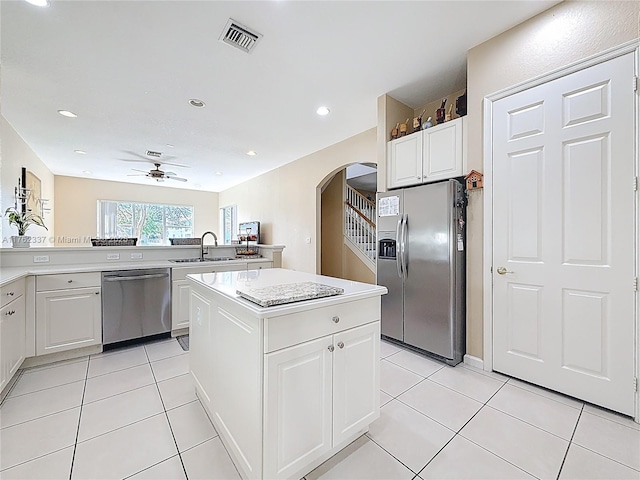 kitchen with visible vents, arched walkways, a sink, stainless steel appliances, and a center island