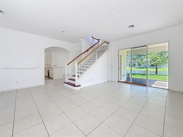 2217 SW Newport Isles Blvd, Port St Lucie, FL 34953 - empty room with light tile patterned flooring, stairs, and arched walkways