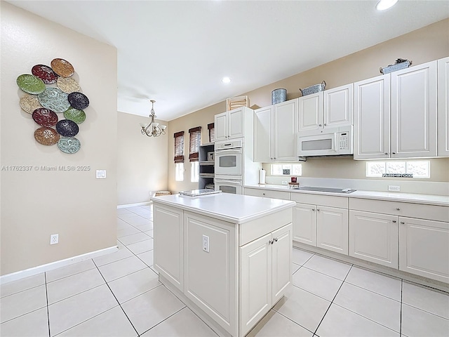 kitchen with light tile patterned floors, white appliances, a kitchen island, and light countertops