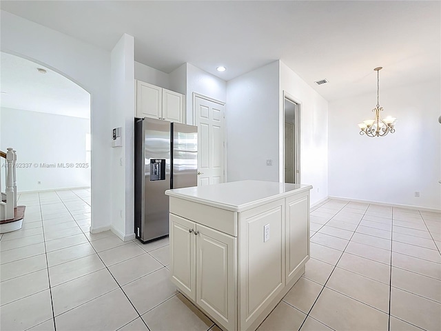 2217 SW Newport Isles Blvd, Port St Lucie, FL 34953 - kitchen with stainless steel fridge, arched walkways, light tile patterned flooring, white cabinets, and a chandelier