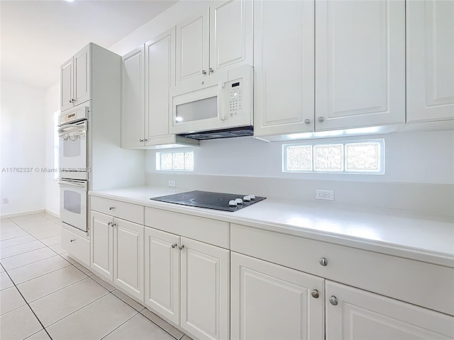 2217 SW Newport Isles Blvd, Port St Lucie, FL 34953 - kitchen featuring white appliances, light countertops, light tile patterned floors, and white cabinets