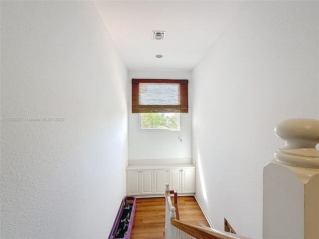 stairway with visible vents and wood finished floors