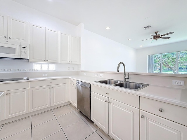 2217 SW Newport Isles Blvd, Port St Lucie, FL 34953 - kitchen with white microwave, dishwasher, light tile patterned floors, light countertops, and white cabinets