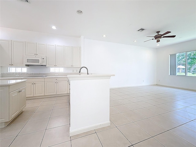 2217 SW Newport Isles Blvd, Port St Lucie, FL 34953 - kitchen featuring white microwave, light tile patterned floors, light countertops, black electric cooktop, and a ceiling fan