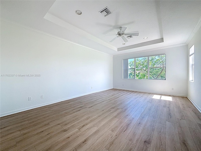 2217 SW Newport Isles Blvd, Port St Lucie, FL 34953 - empty room with a tray ceiling, healthy amount of natural light, a ceiling fan, wood finished floors, and ornamental molding